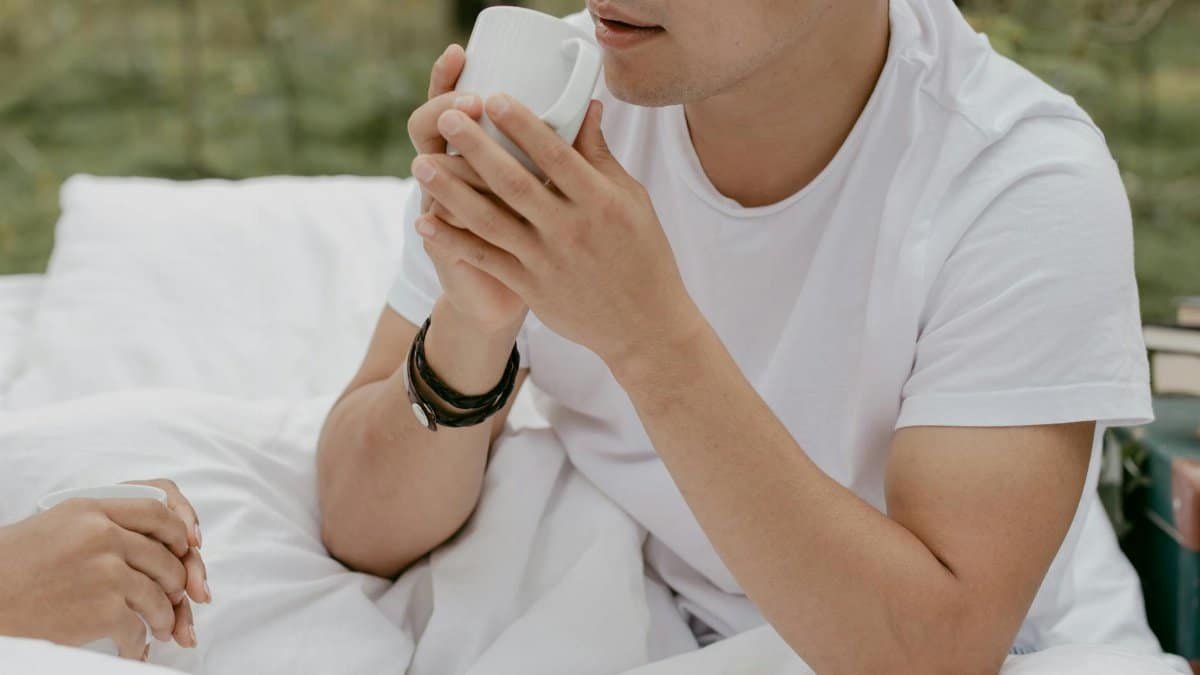 Man enjoying a cup of coffee outdoors, wrapped in a blanket, exuding a relaxed morning vibe.