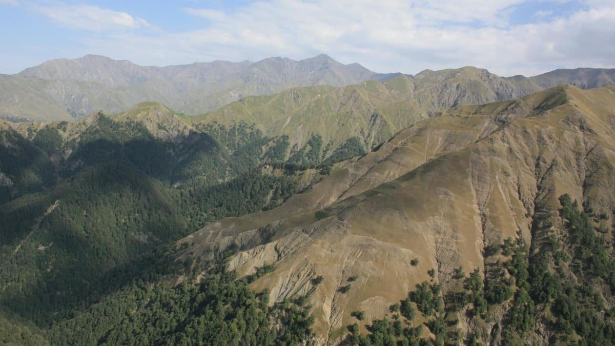 Breathtaking view of a mountain range with lush greenery under a clear blue sky.