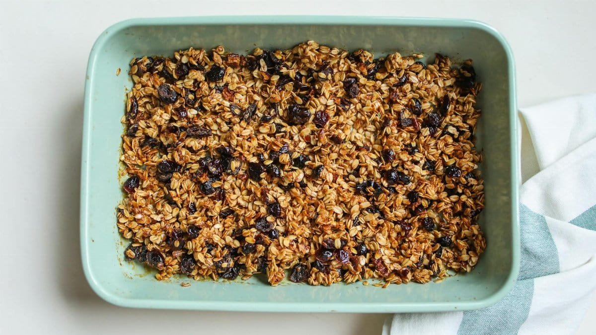 Freshly baked granola with oats and raisins in a blue baking dish for a healthy breakfast.