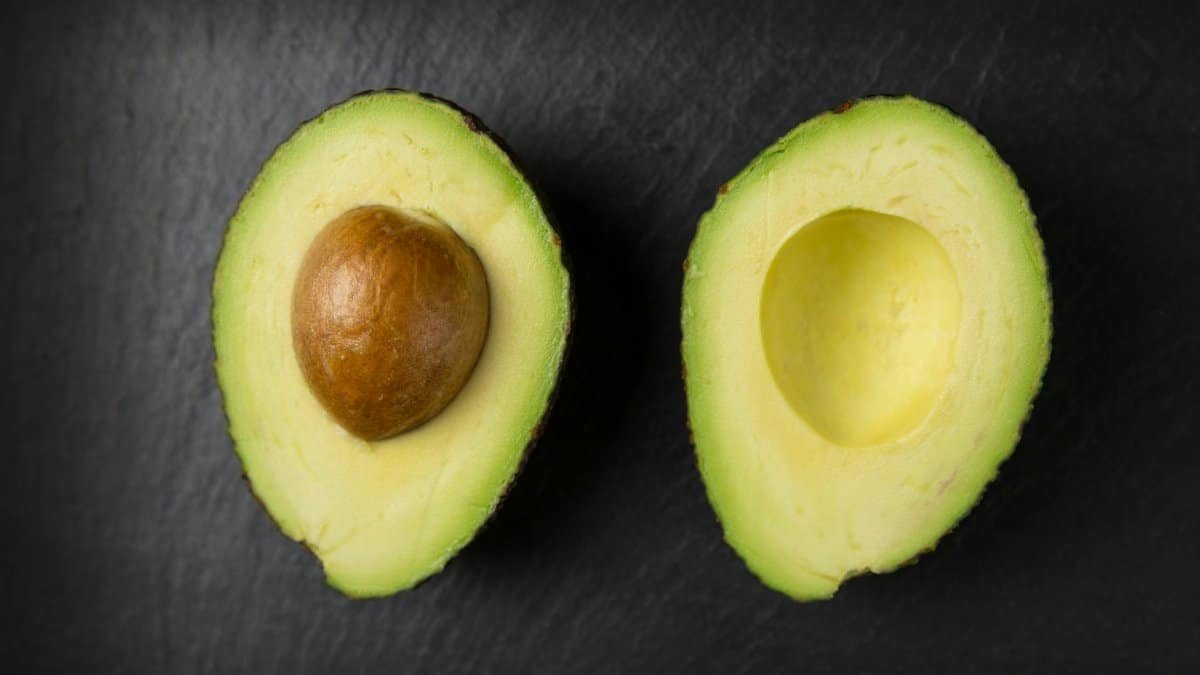 Close-up of fresh sliced avocado halves on a dark slate surface, showcasing healthy eating.