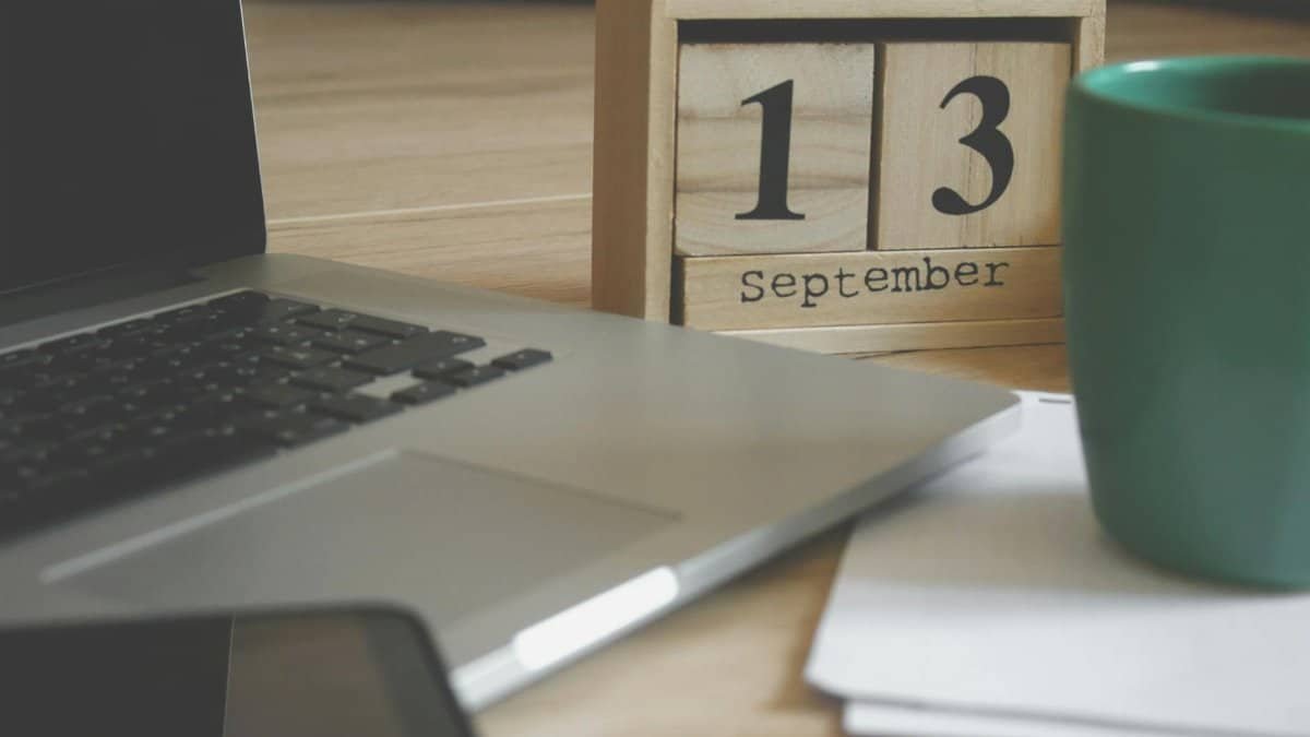 Modern home office setup with a laptop, smartphone, and calendar displaying September 13.