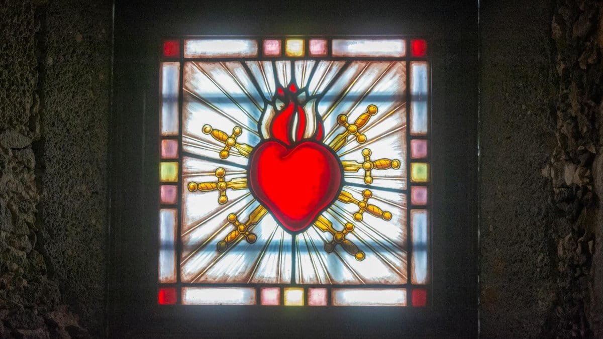 Vibrant stained glass depicting Sacred Heart in a church setting, symbolizing love and devotion.