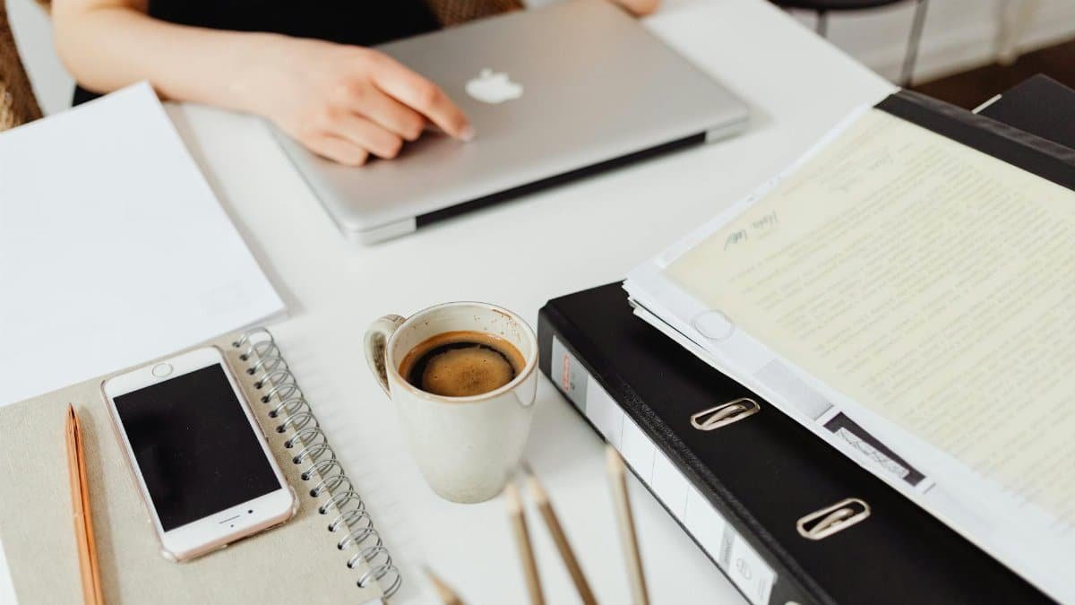 A clean workspace featuring a laptop, coffee, smartphone, and documents for efficient work.