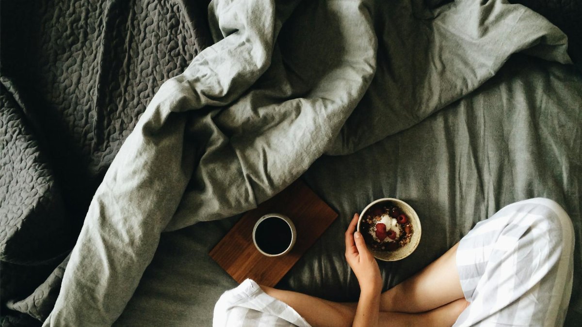 A peaceful morning scene featuring a woman enjoying breakfast and coffee in bed.