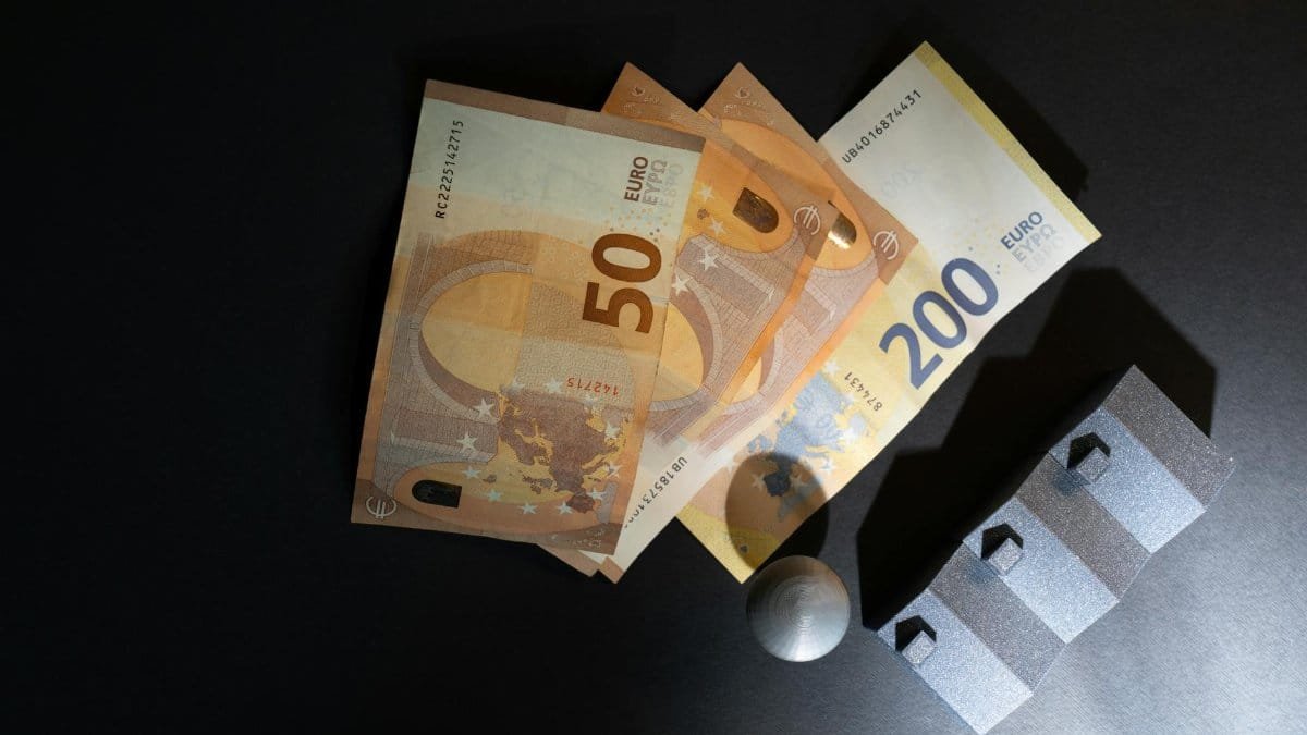 Close-up of Euro banknotes and model houses on dark background symbolizing real estate investment.