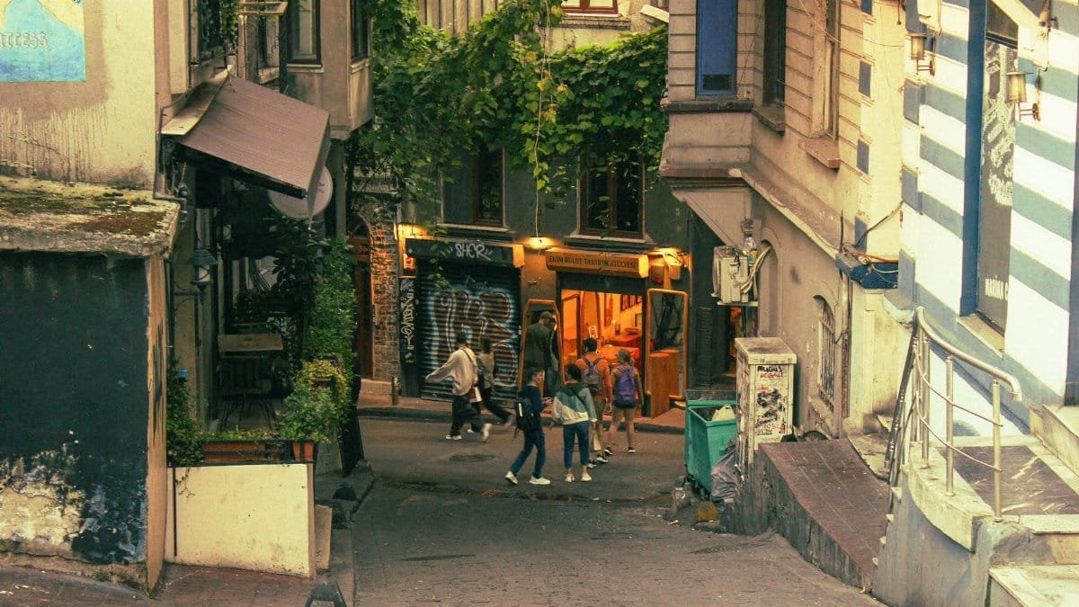 A picturesque alleyway with colorful street art and people walking, creating a vibrant urban scene.