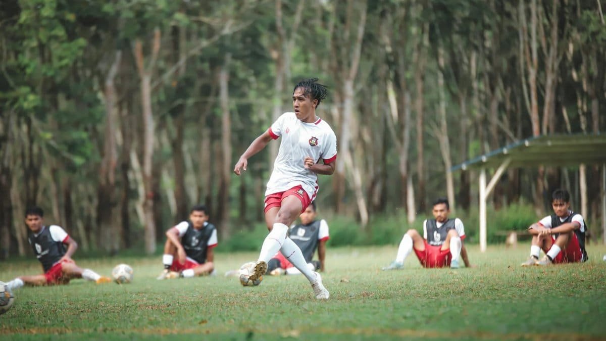 A dynamic soccer player in action during an outdoor training session with teammates in the background.