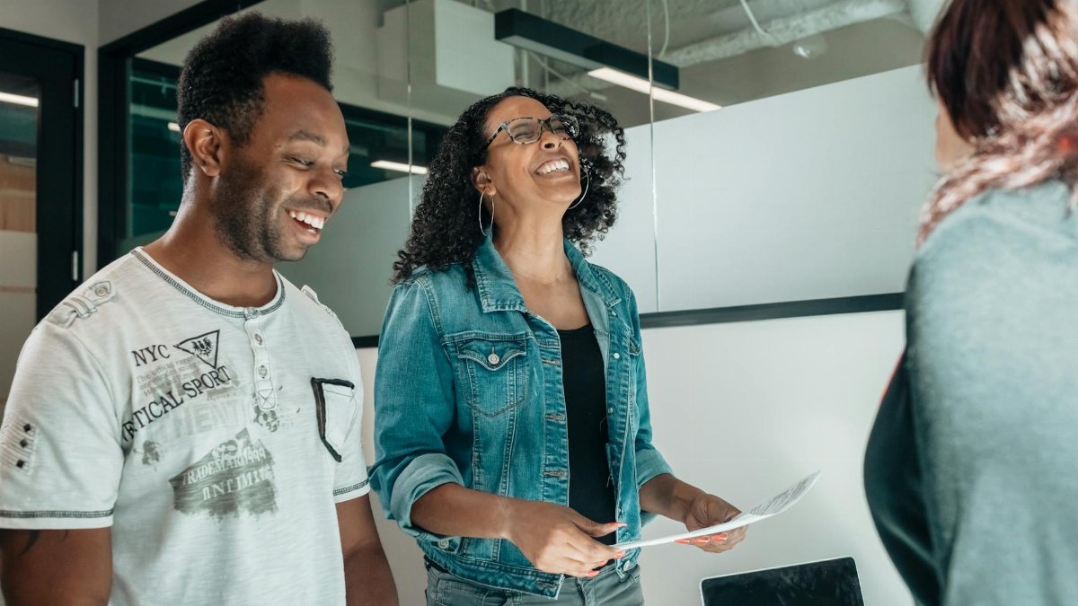 Smiling couple discussing with an advisor in a modern office setting.