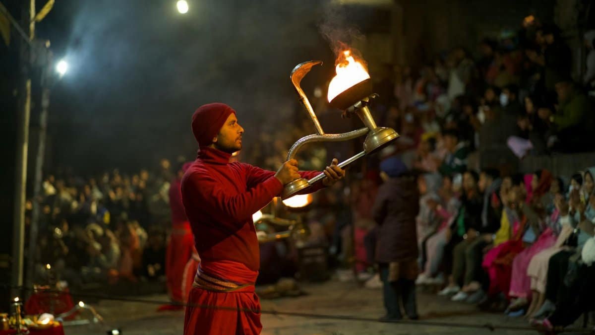A Hindu priest performs an evening ritual with a fire lamp in a crowded Nepal temple.