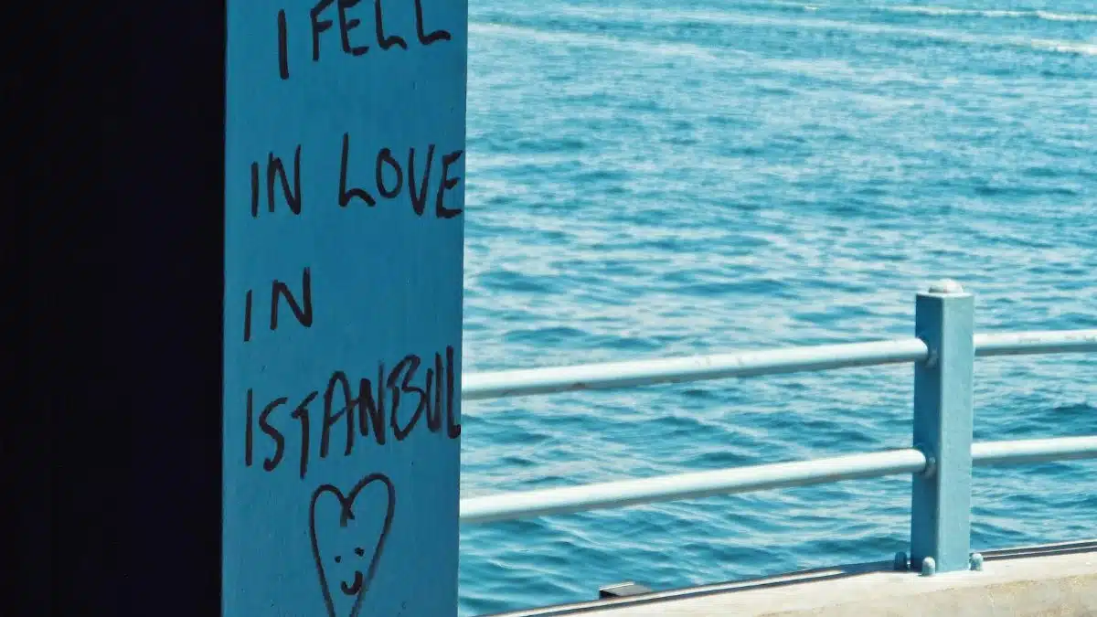 Graffiti reading 'I fell in love in Istanbul' with a heart by the sea.