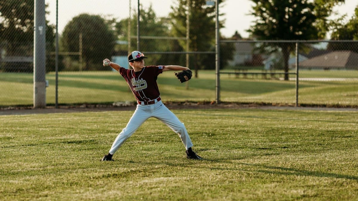 A young boy playing baseball on a sunny day in Kansas City, MO, showcasing his pitching skills on the field.