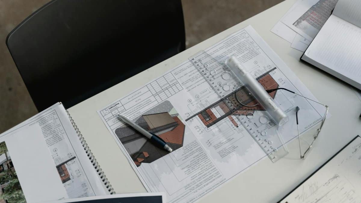 Top view of architectural blueprints and drafting tools on a workspace desk.