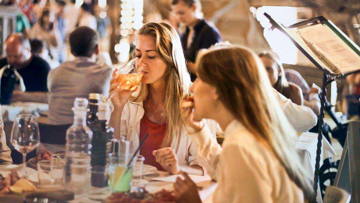 Friends dining in a cozy Italian restaurant, enjoying drinks and food in a lively atmosphere.