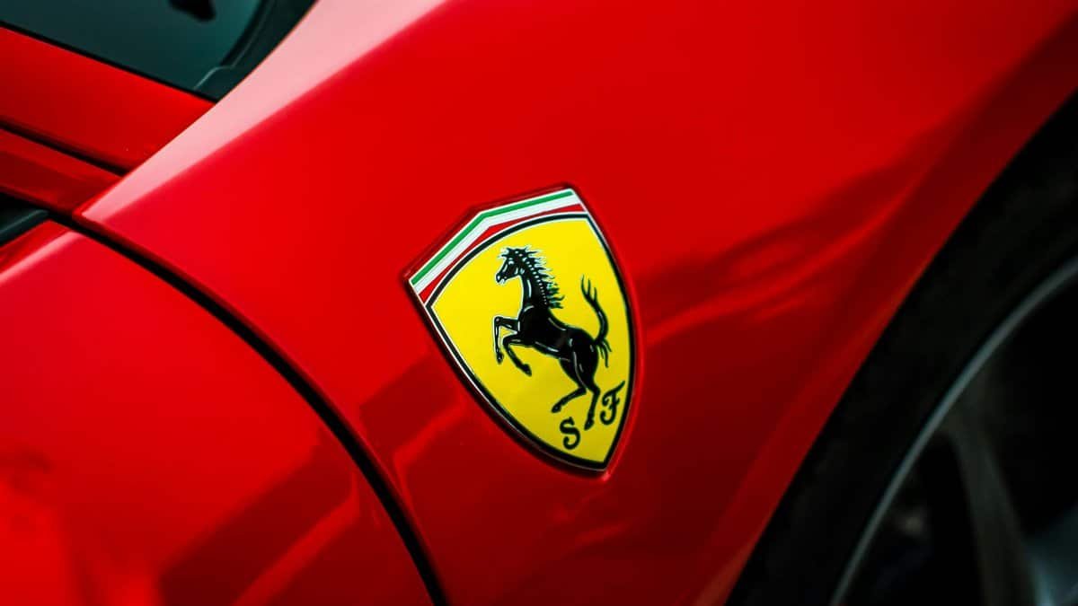 Detailed view of a luxury car emblem on a sleek red sports car, showcasing elegance and style.