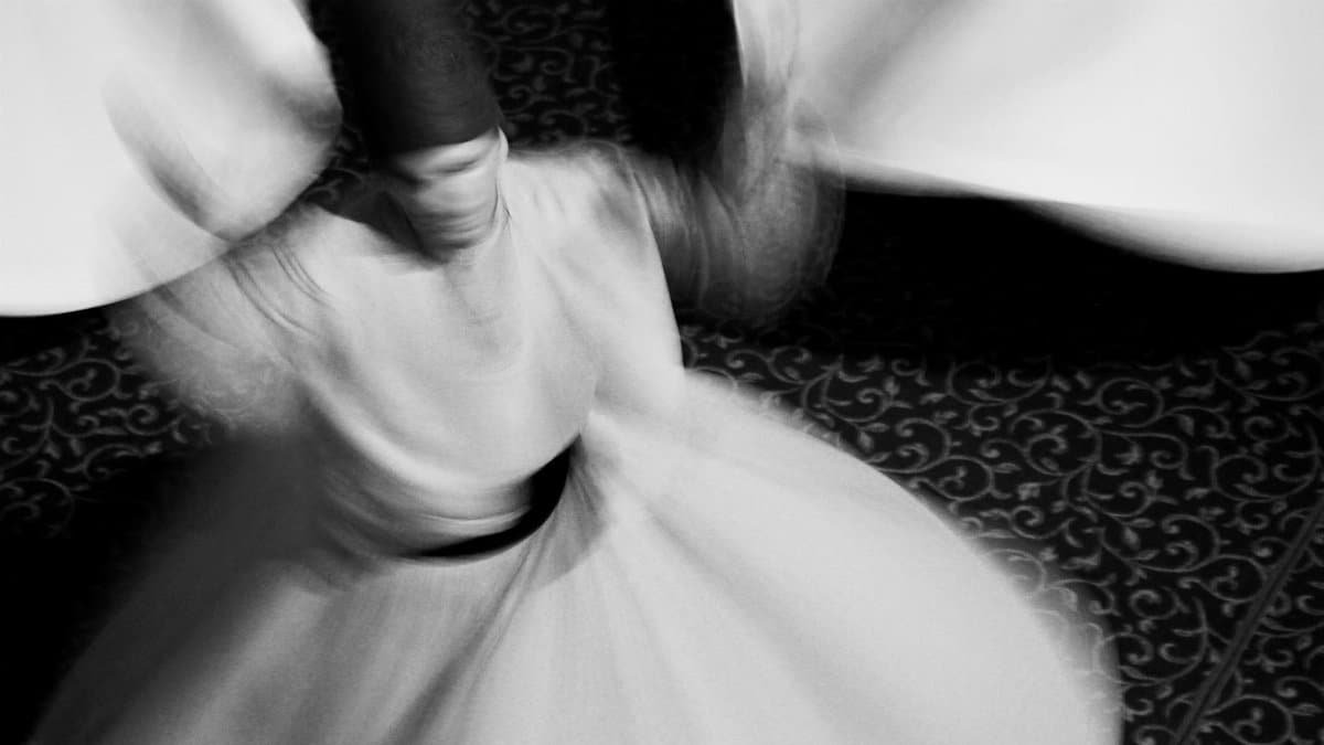 Blurred motion of a Sufi whirling dervish, showcasing spiritual dance and white attire.