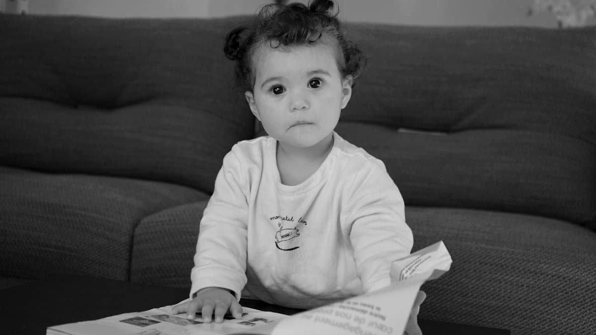 Cute baby engaged and curious while looking at a book indoors.