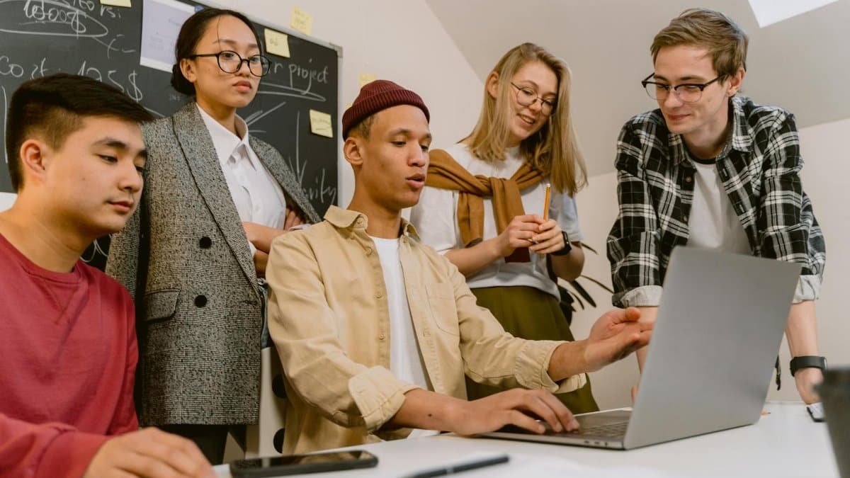 A diverse team of young professionals brainstorming with a laptop in a modern office.