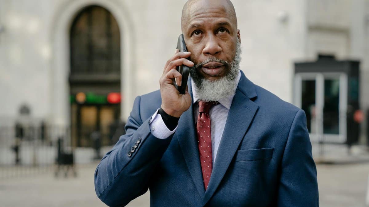 Mature businessman in a suit using a smartphone while standing outdoors.