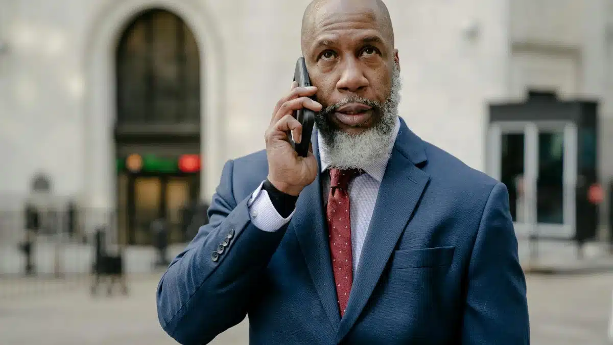 Mature businessman in a suit using a smartphone while standing outdoors.