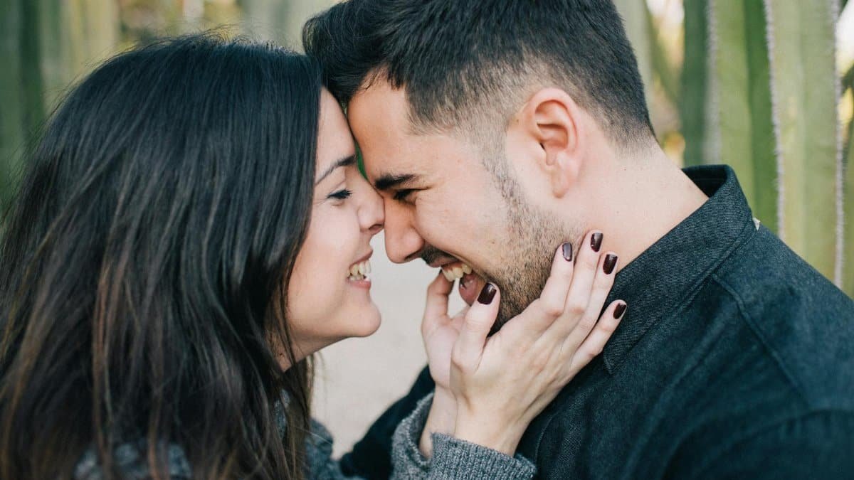 Young couple sharing a tender moment outdoors, surrounded by greenery, radiating love and happiness.