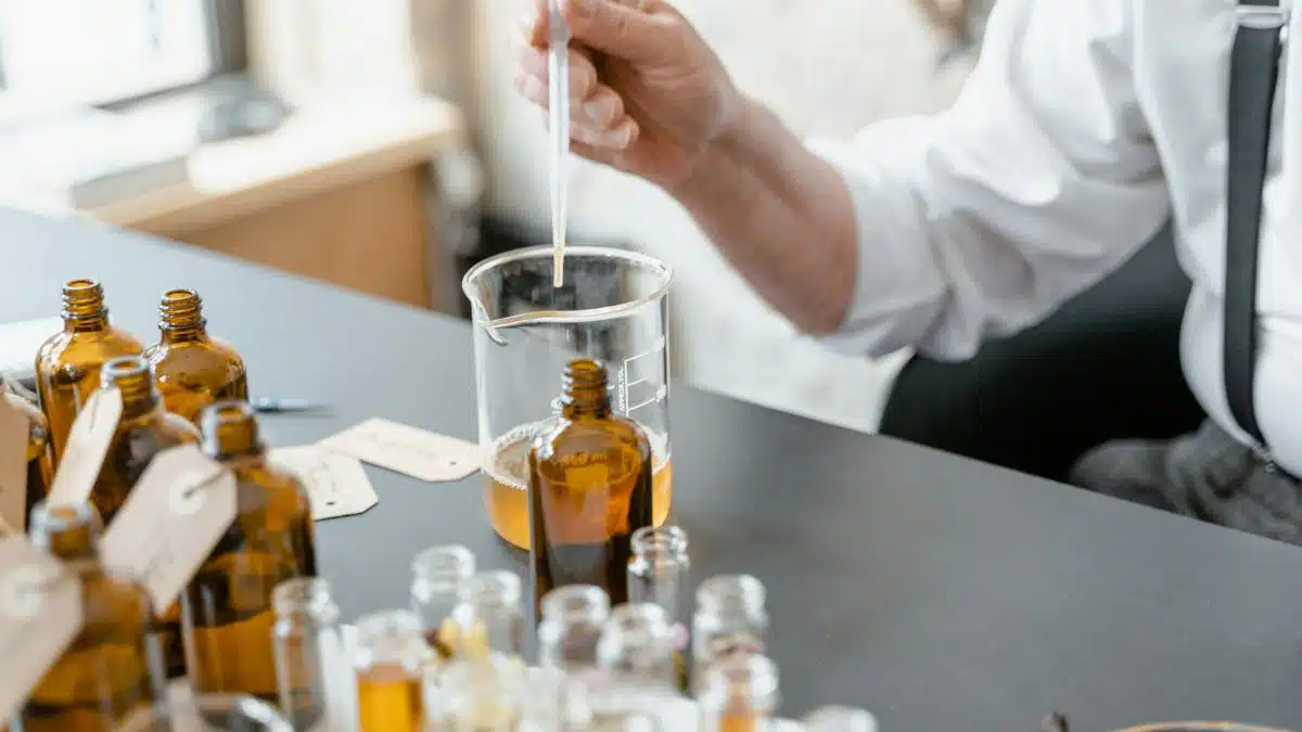 A person blends essential oils in glass bottles for aromatherapy indoors.