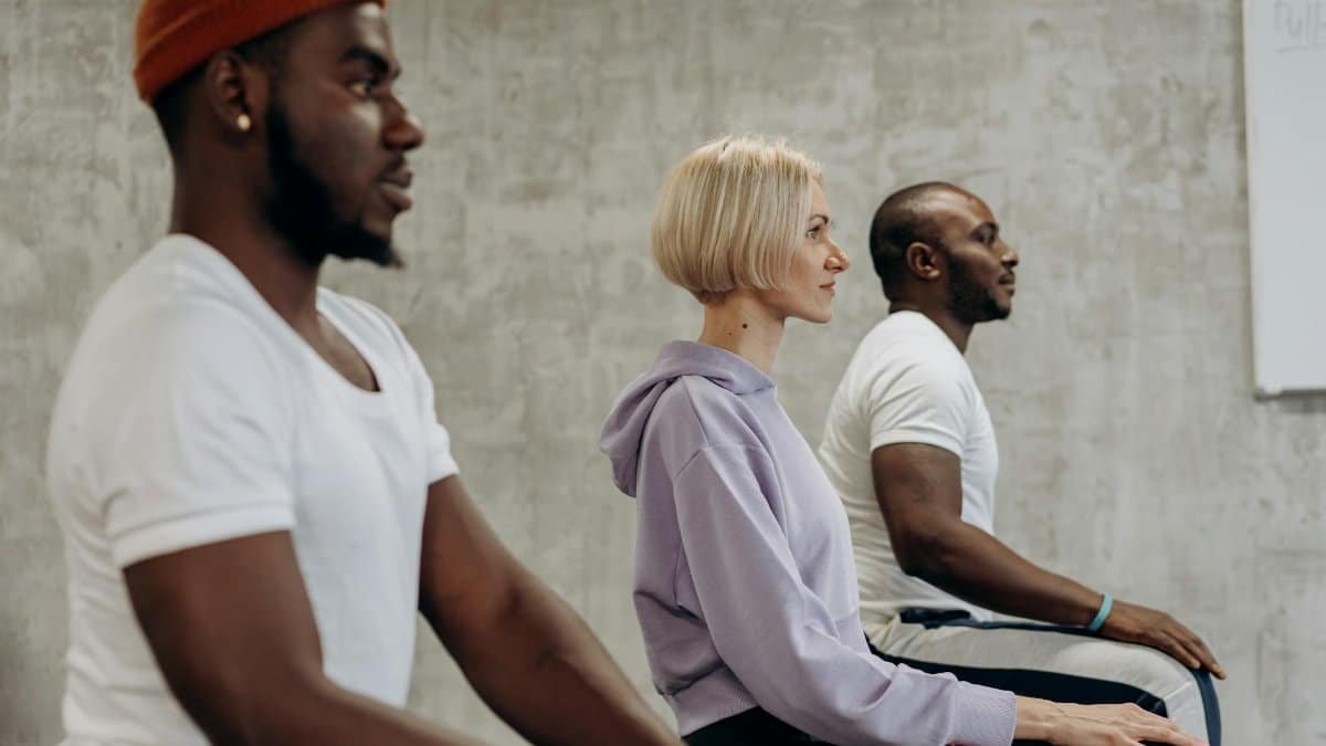 Three people practicing meditation indoors, focusing on relaxation and wellness.