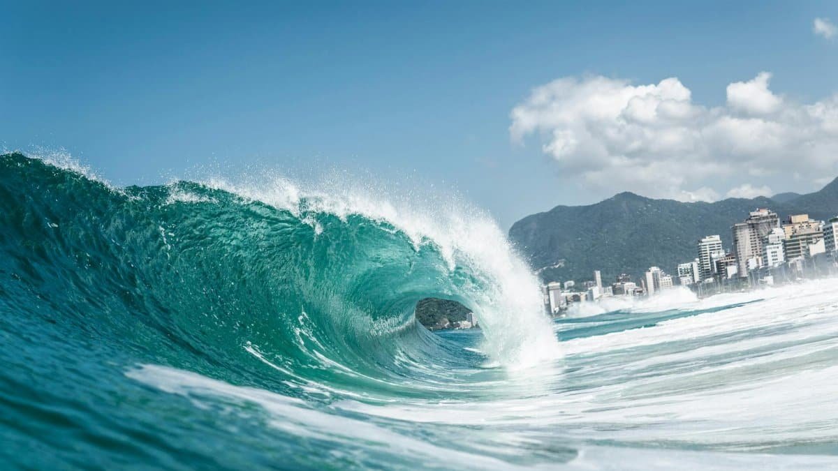 Dynamic ocean wave crashing near Ipanema Beach, Rio de Janeiro under a clear sky.