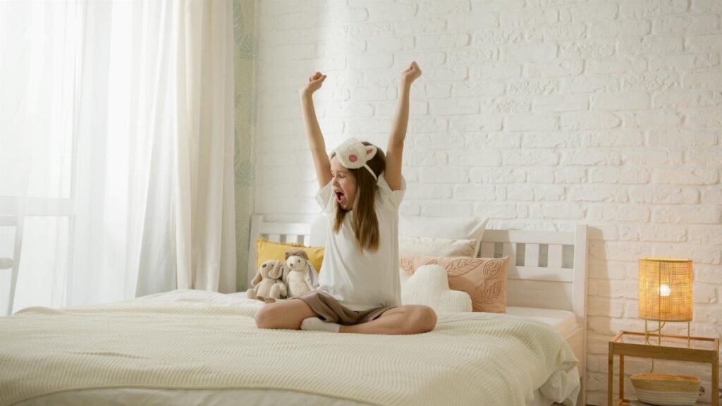 A young girl wakes up and stretches in her comfortable bedroom, feeling refreshed and joyful.