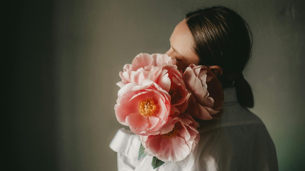 A woman holding a bouquet of pink peonies, exuding a dreamy and romantic vibe.
