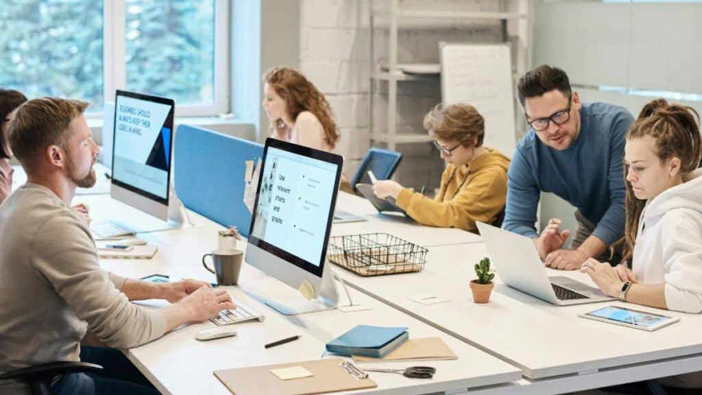 Team collaboration in a modern office setting with computers and diverse employees working together.