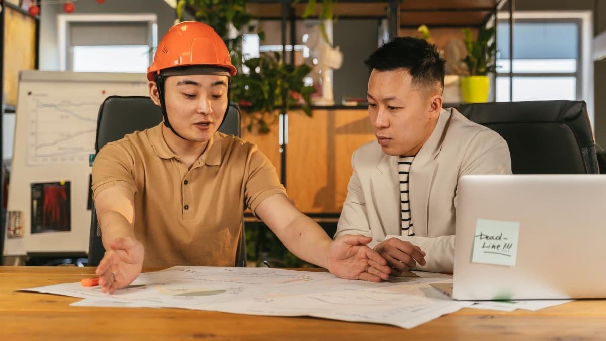 Two engineers discussing project plans in a modern office setting, emphasizing teamwork and collaboration.