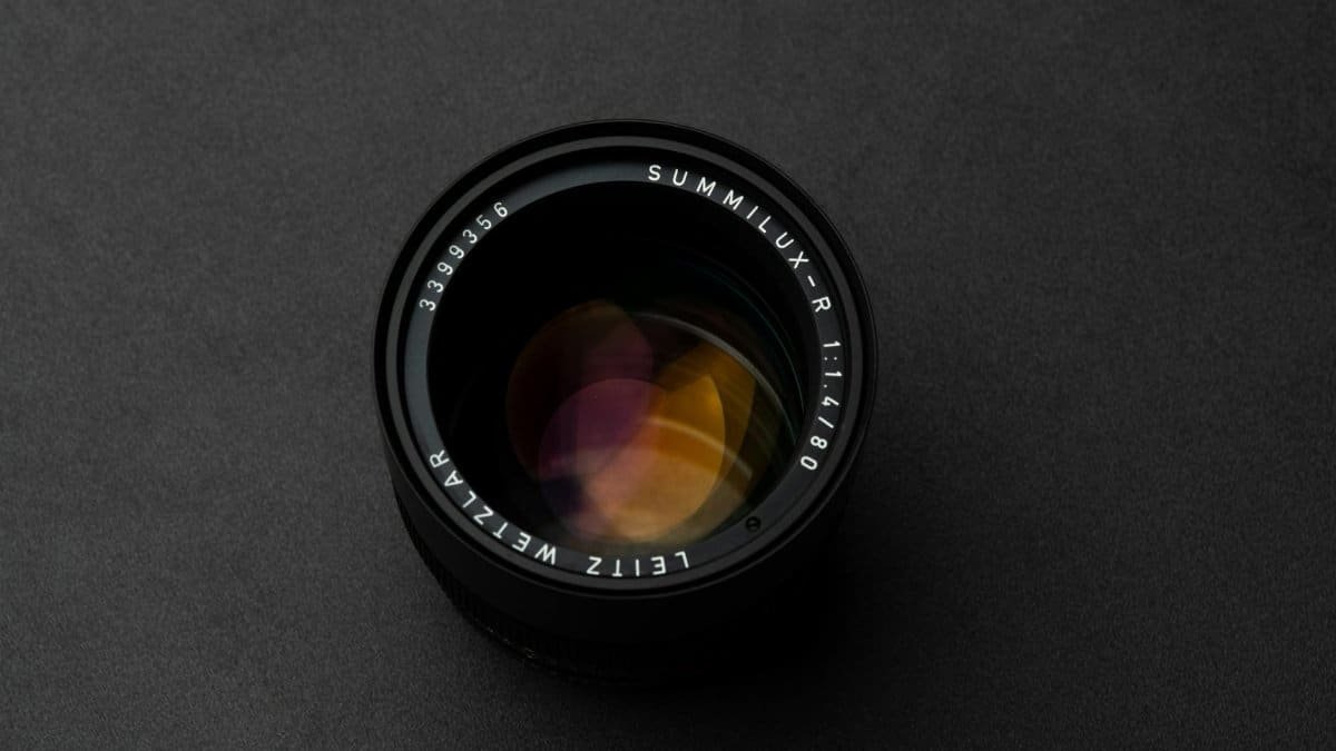 High-contrast photo of a camera lens on a dark background, showcasing design and focus.