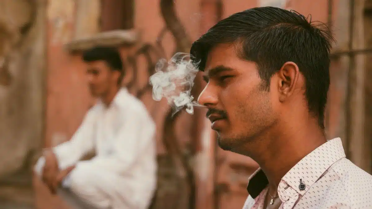 A contemplative young man smokes on a vibrant street in İstanbul, capturing urban life.