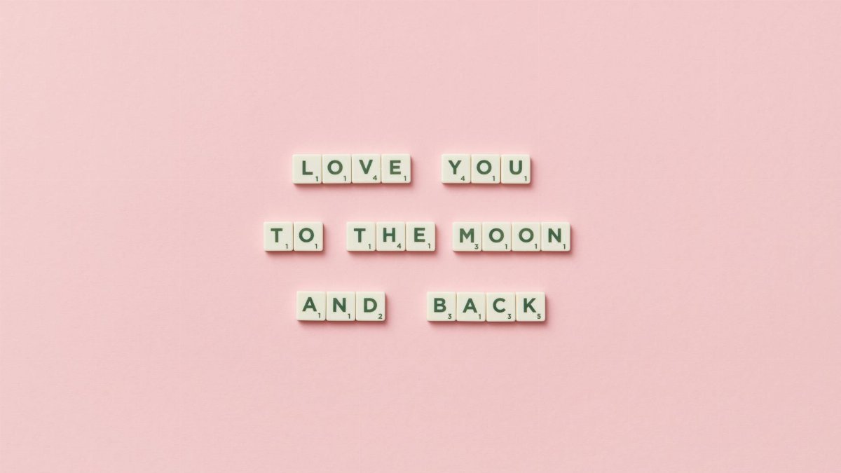 Letter tiles spelling 'Love You to the Moon and Back' on a pink background.