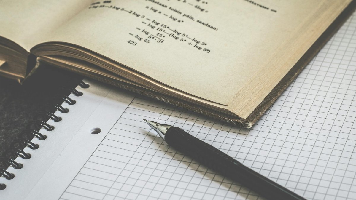 Mathematical study scene with open book, graph paper, and pen for learning and homework.
