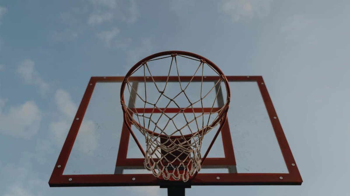 Photo of a basketball hoop with a transparent backboard against a clear blue sky, ideal for sports themes.