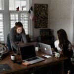 Two young women working collaboratively in a cozy home office setting.