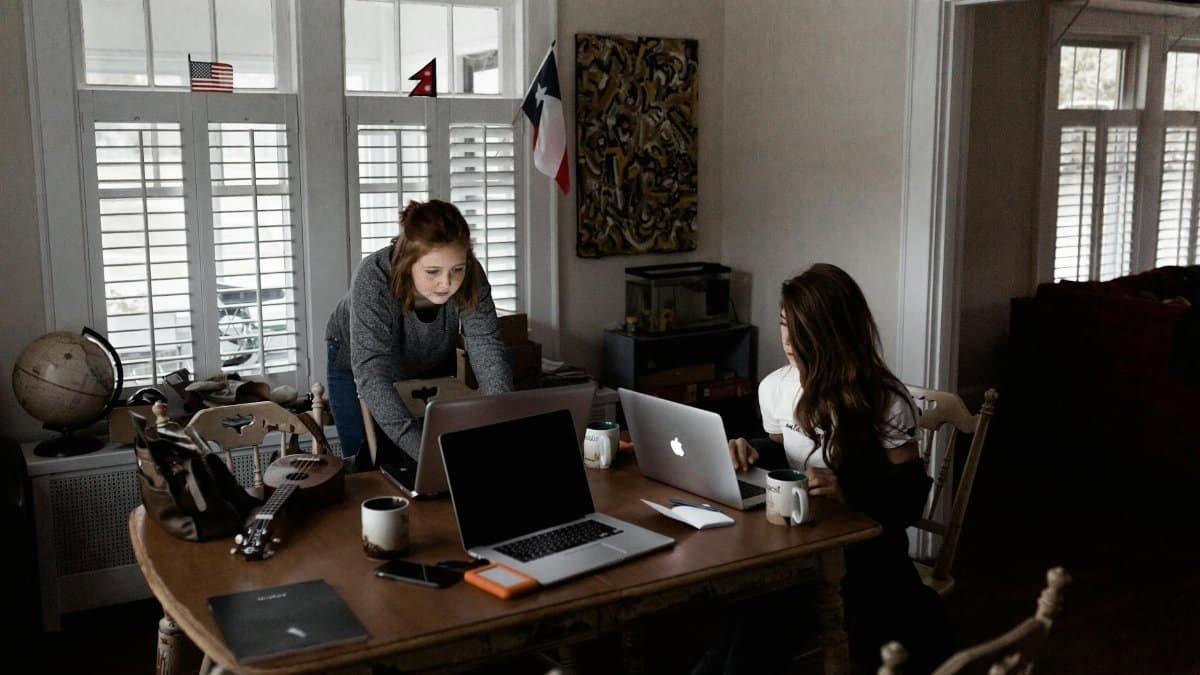 Two young women working collaboratively in a cozy home office setting.