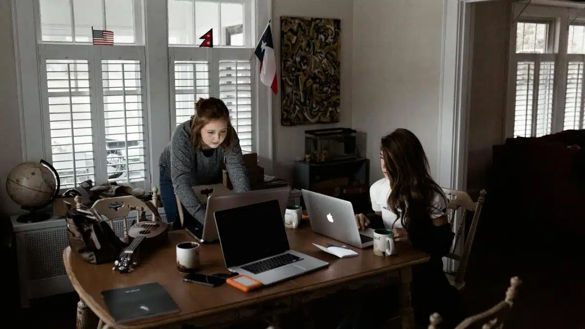 Two young women working collaboratively in a cozy home office setting.