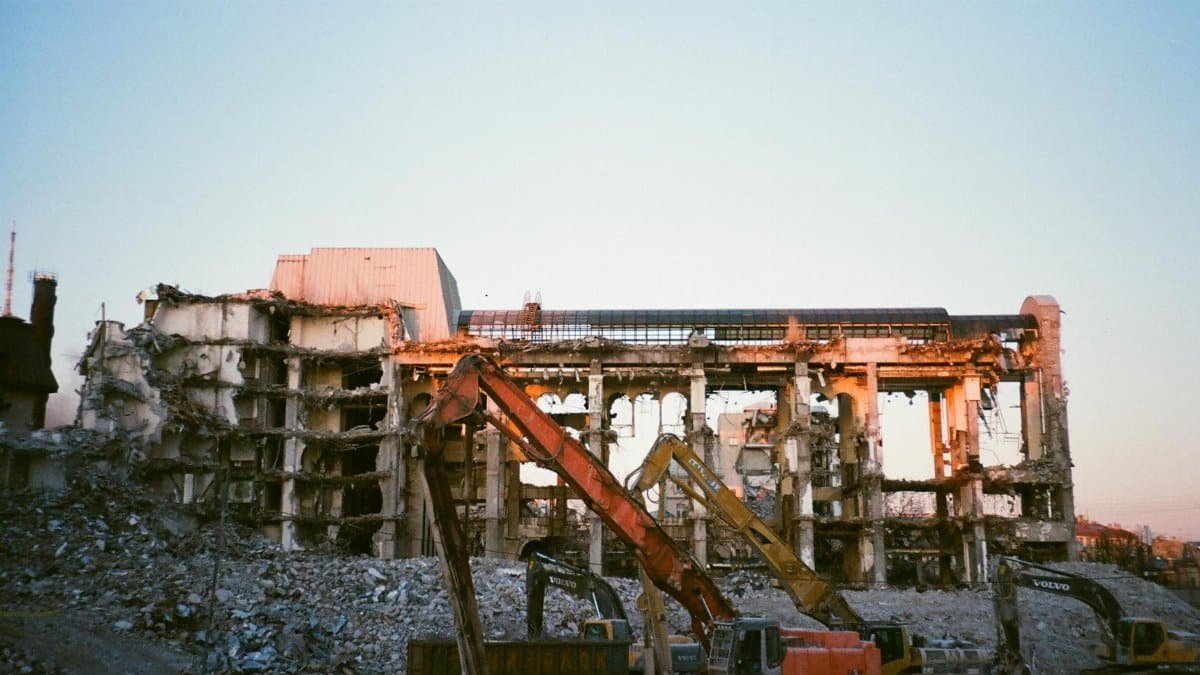 Construction machinery at a building demolition site during sunset.