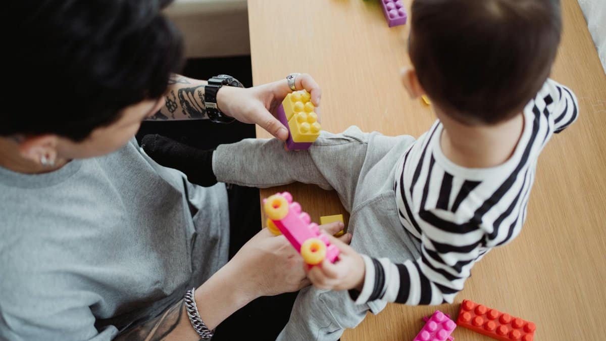 Father and child bonding over colorful building blocks indoors, fostering creativity and connection.