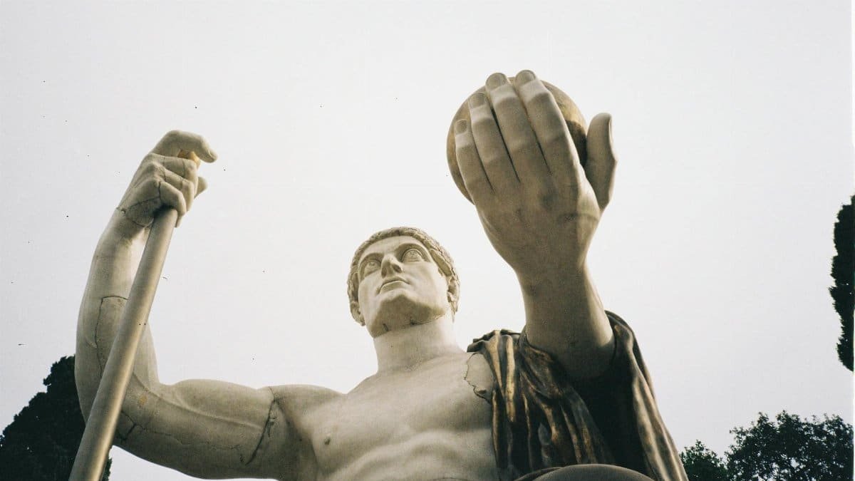 A dramatic low-angle view of a marble sculpture reaching towards the sky.