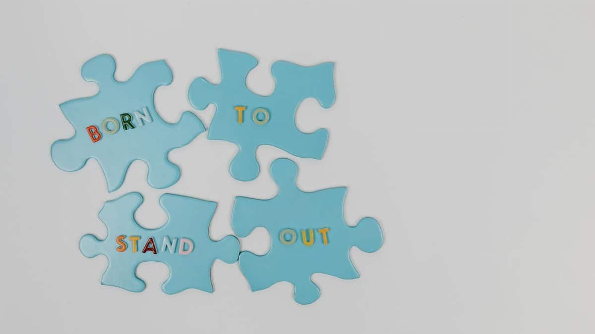 Blue puzzle pieces spelling 'Born to Stand Out' on white background.