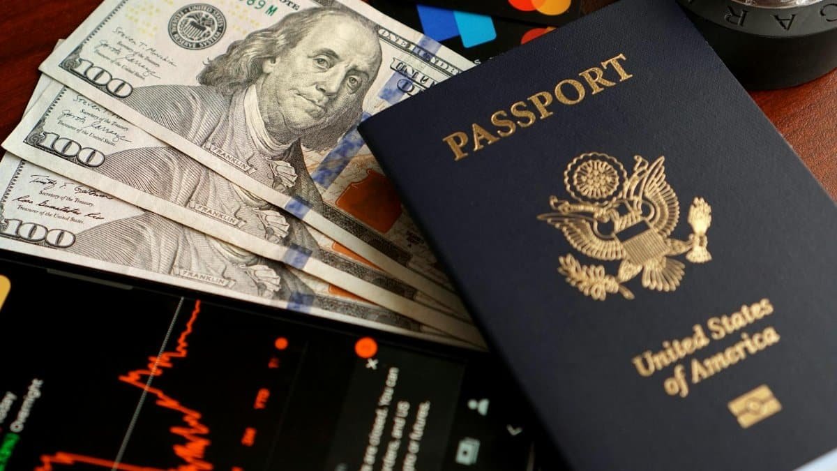 Close-up of US currency, passport, and financial tools for travel and budgeting.