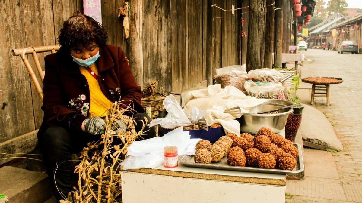 A street vendor in a traditional village setting selling local snacks on a quiet day.