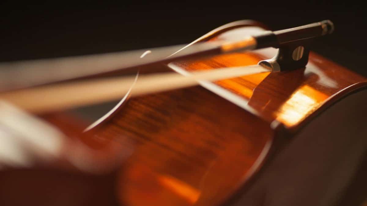 Artistic close-up of a violin with a bow, highlighting warm tones and textures.