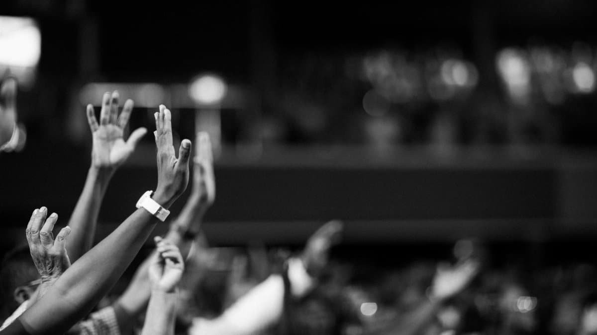 Black and white image of audience with hands raised, capturing concert energy.