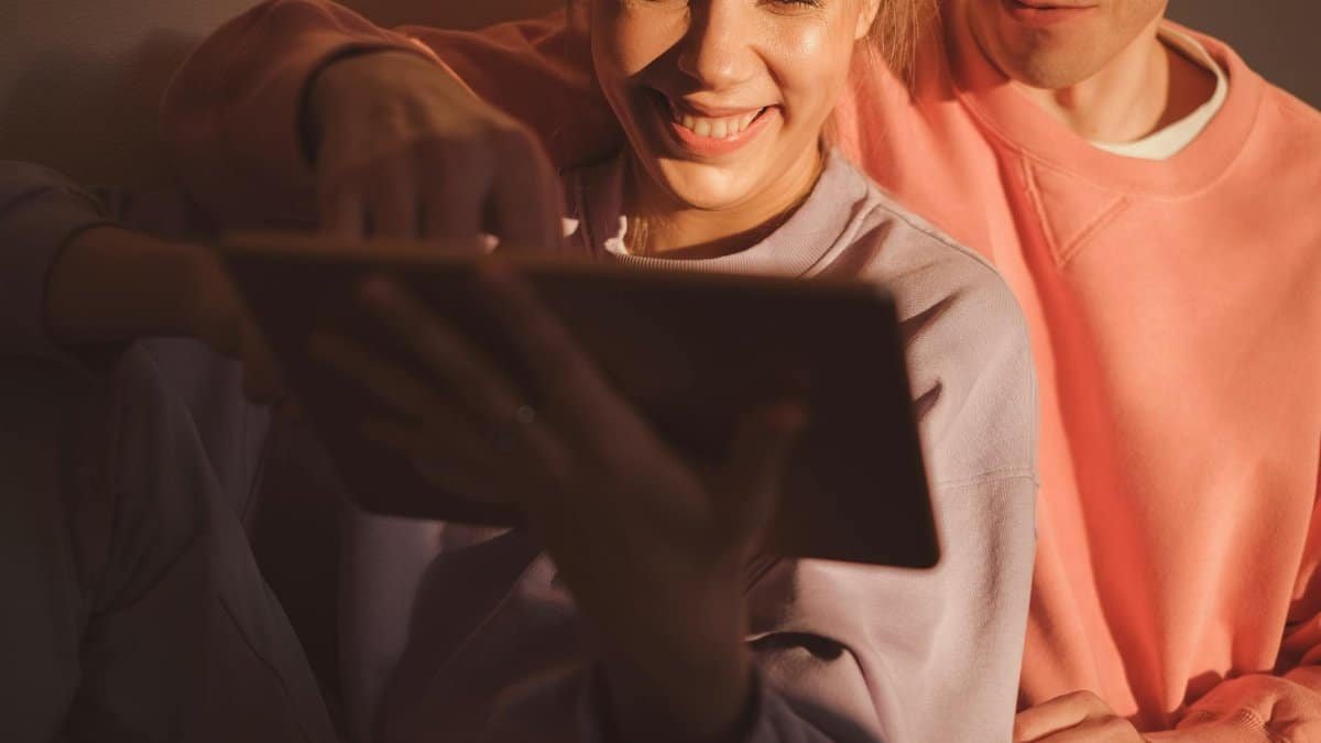 A joyful couple enjoying leisure time and bonding over a digital tablet at home.