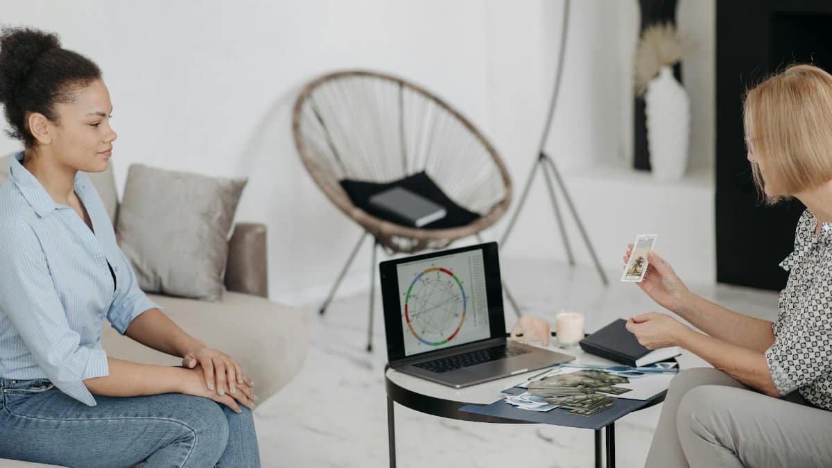 A tarot reader interprets cards and an astrological chart in a serene setting.