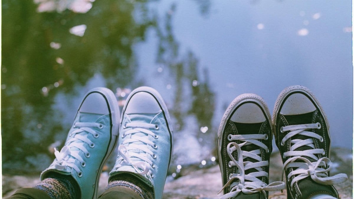 Relaxed moment with sneakers by a tranquil reflective water edge.